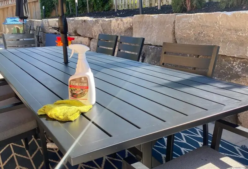 A bottle of Xtreme Clean on top of a beautiful aluminum outdoor dining table