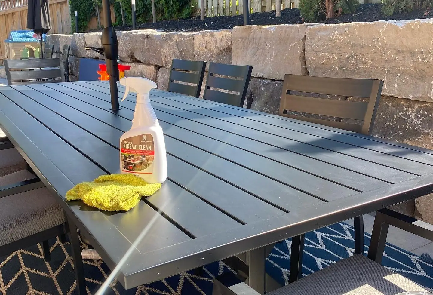 A bottle of Xtreme Clean on top of a beautiful aluminum outdoor dining table