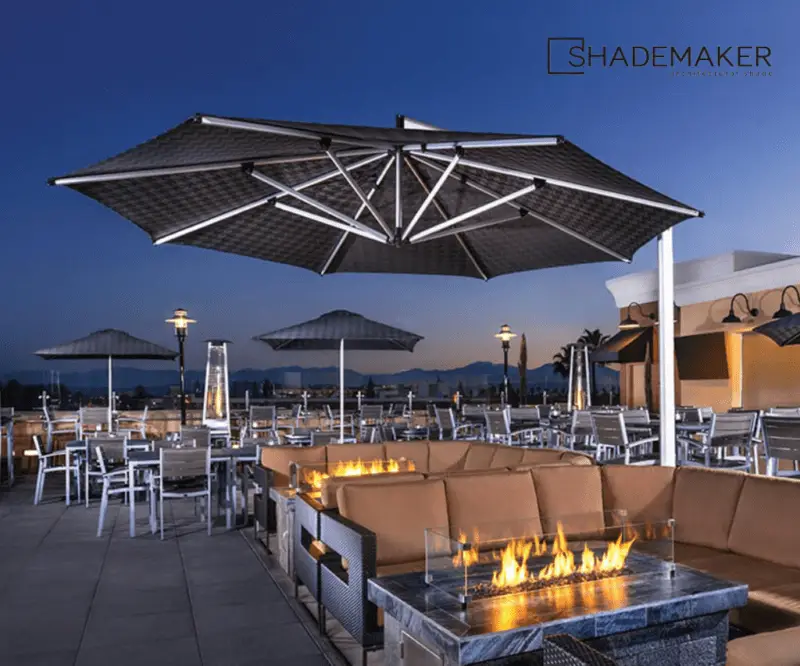 umbrella covering outdoor sectionals with fire tables lit
